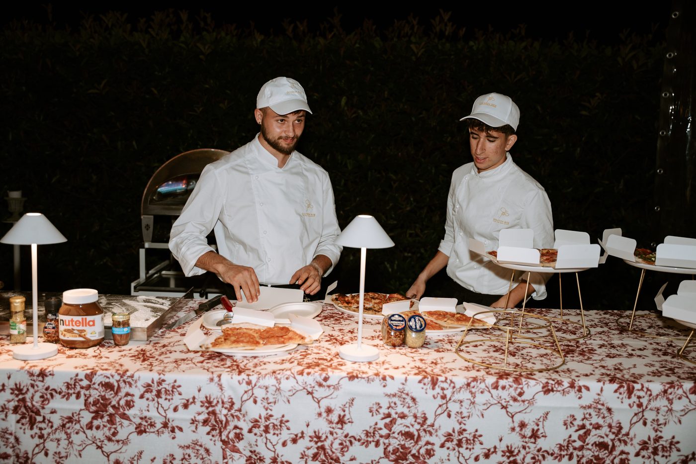 Pizzaiolo Golden Bee taglia una pizza margherita cotta nel forno a legna